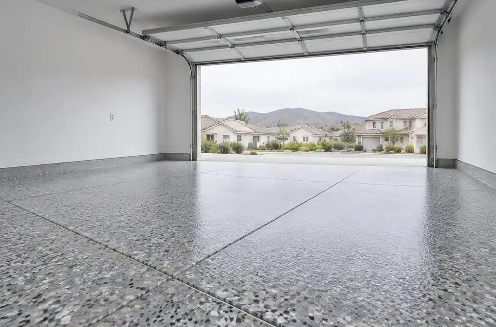 Illustration: a tidy two-car garage in a Murrieta tract home with a glossy gray, tan and white flake floor, wall cabinets, and the garage door open to a sunny driveway